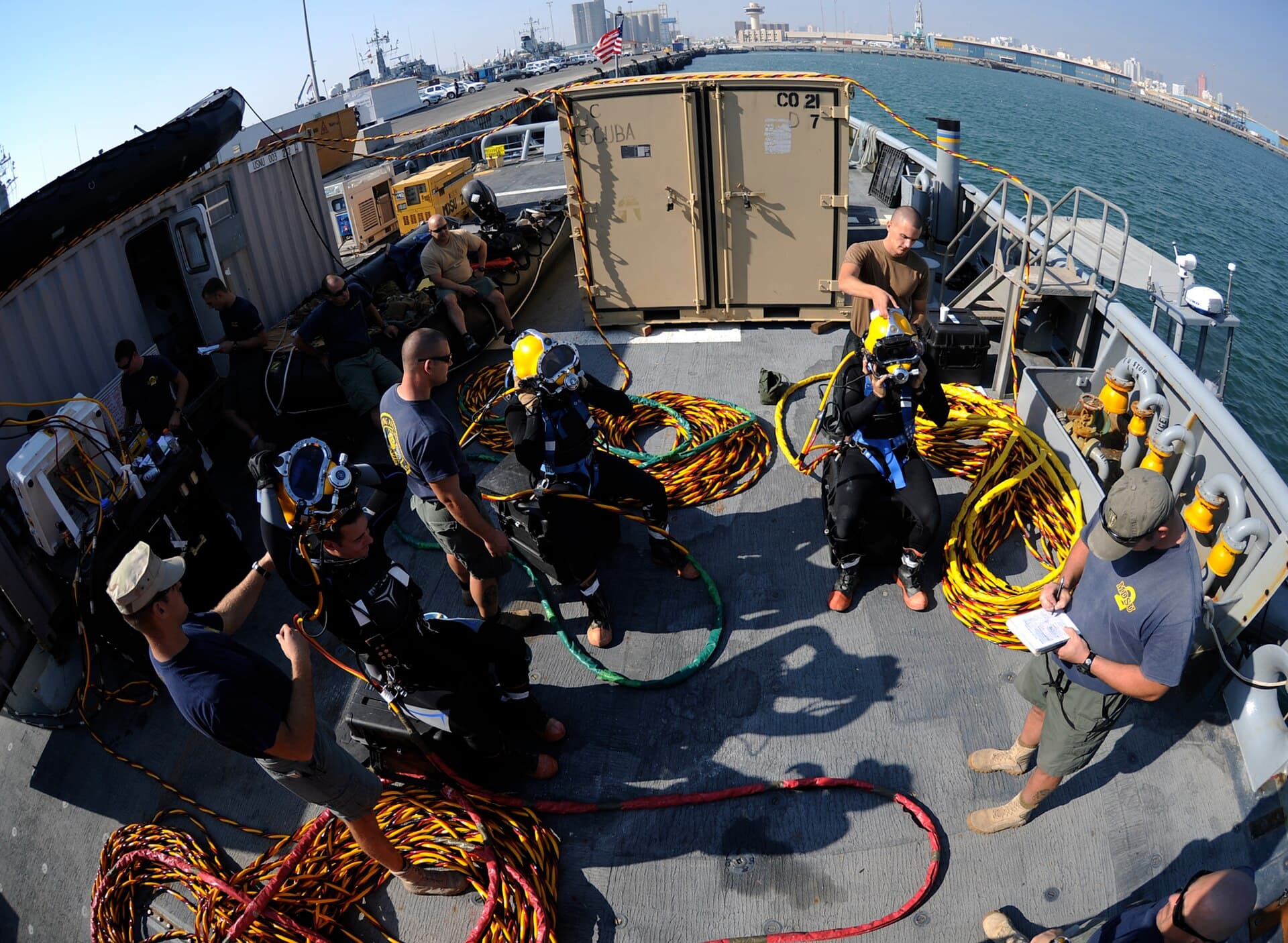 U.S. Navy divers preparing for a surface-supplied air dive with umbilicals coiled on deck